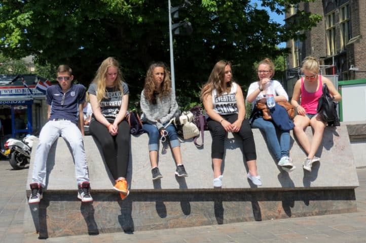 Zes jongeren naast elkaar op straatbank