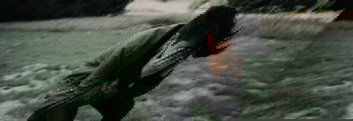 jongen leunt op een knie en houdt handen voor gezicht