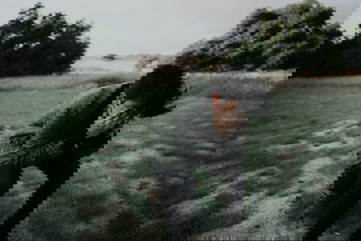 jongen leunt op een knie en houdt handen voor gezicht