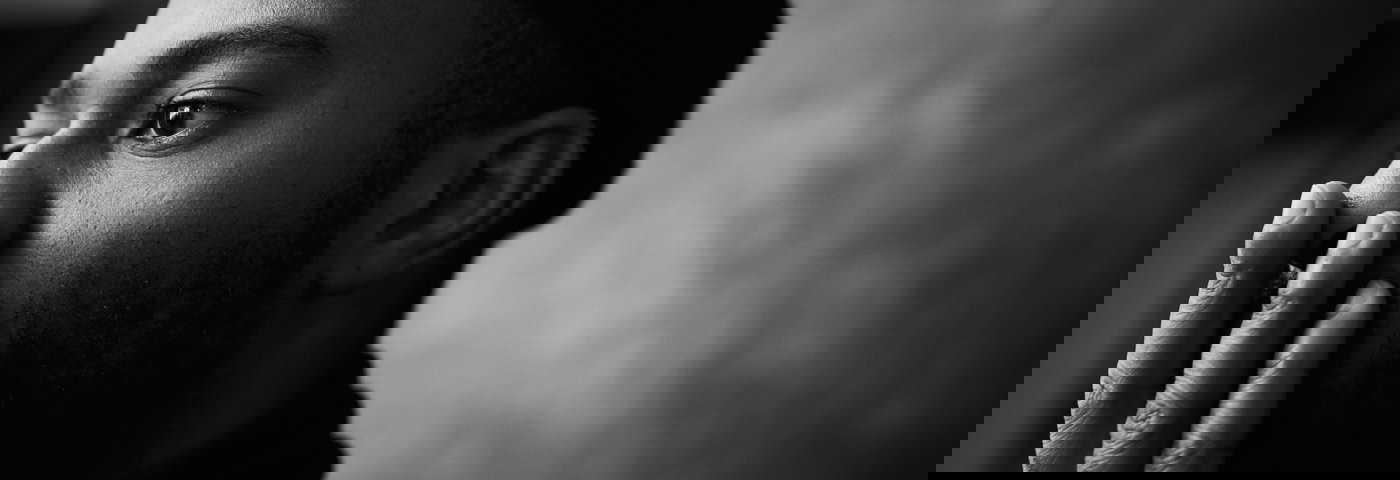 Zwart-wit foto van man die hand voor de mond houdt.