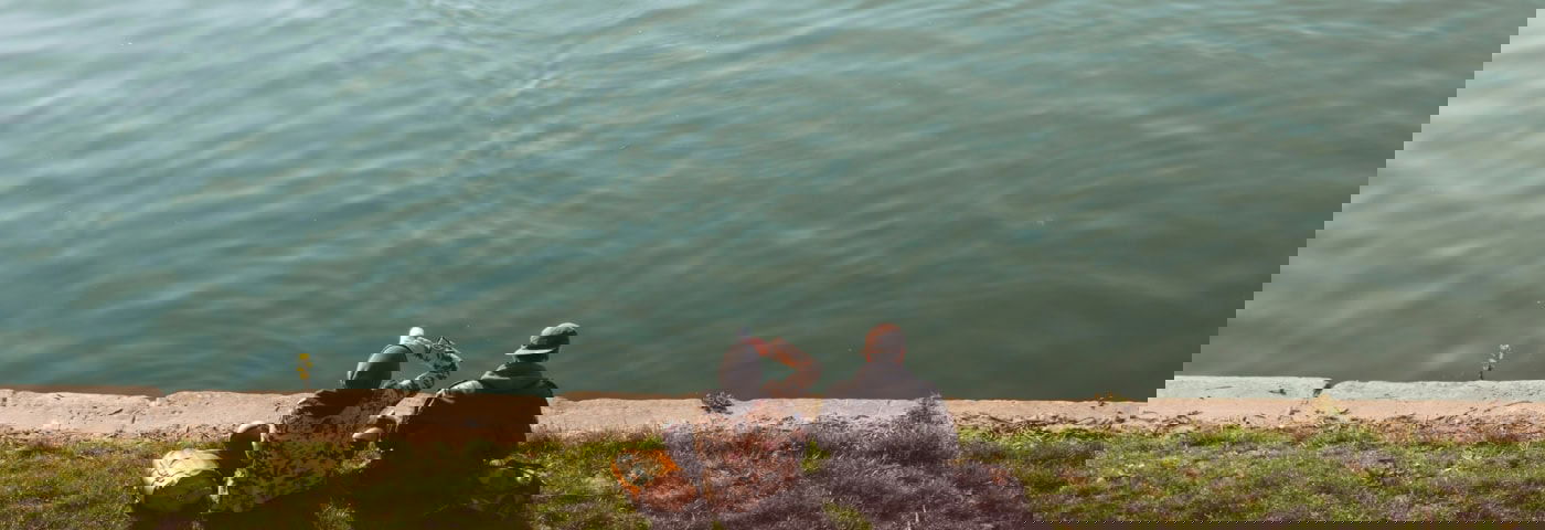 Twee mensen zitten aan het water.